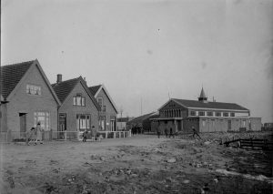 Kerk en school te Den Oever .Het houten schoolgebouw is hier tussen de huizen en de kerk zichtbaar.